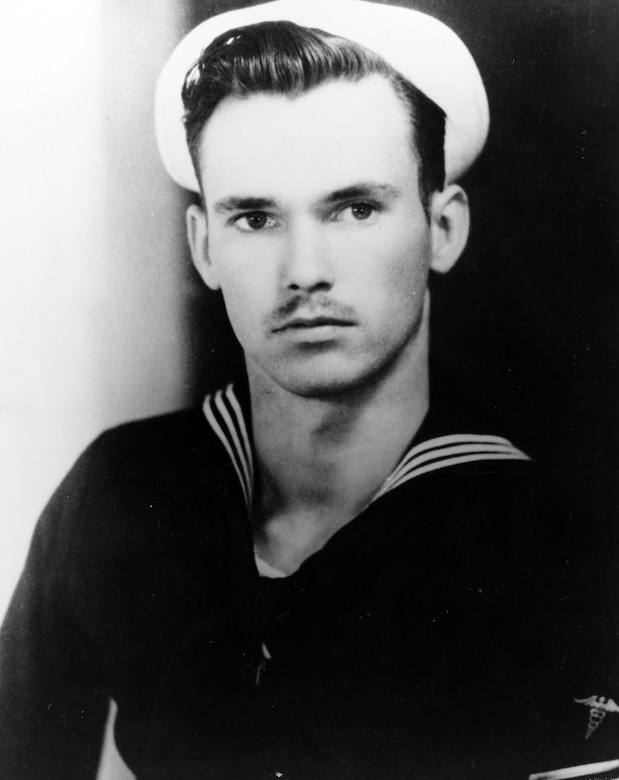 A sailor in uniform looks at the camera.