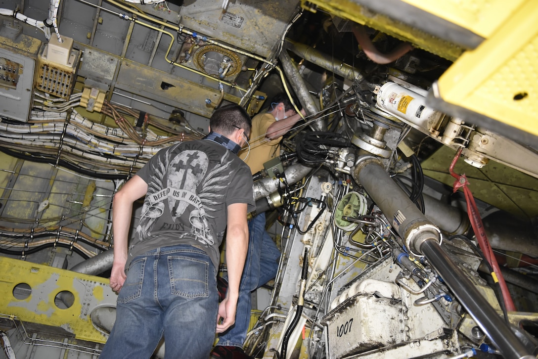 Two men looking at underneath area of aircraft.