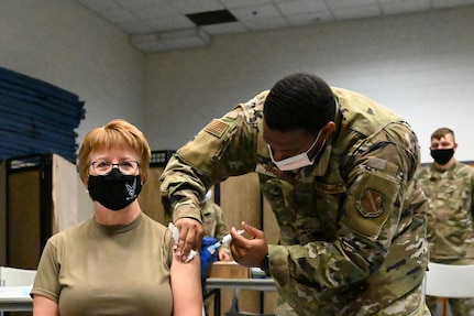 Image of Surgeon General receiving vaccine from an Airman.