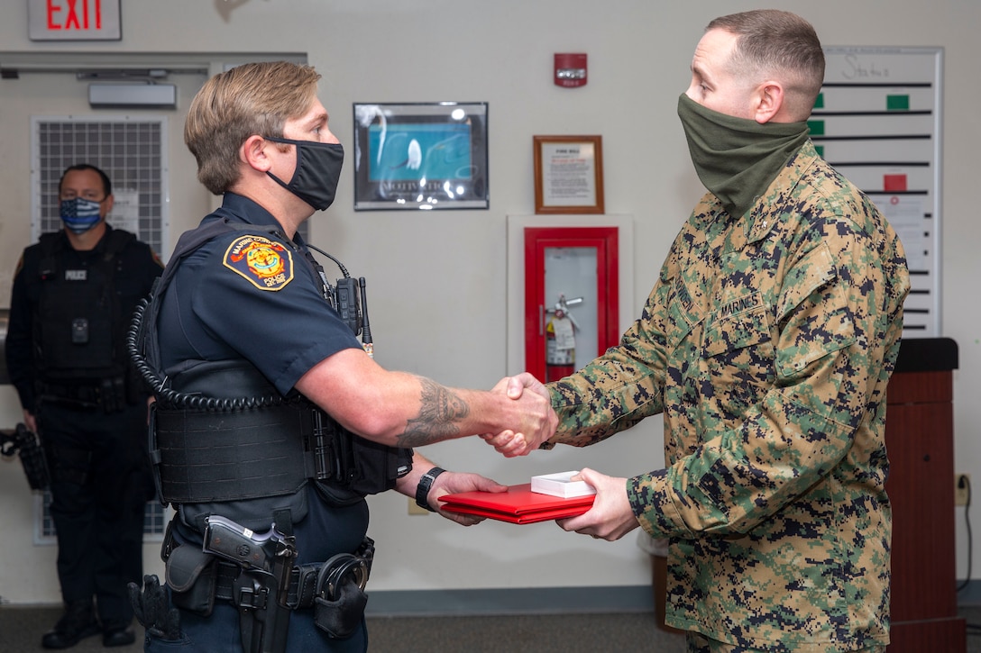 Adam Wallace, left, a police officer with the Marine Corps Base Camp Lejeune Provost Marshal’s Office (PMO), receives the Lifesaving Award from Lt. Col. Matthew Dowden, right, commanding officer of 2nd Tank Battalion, 2nd Marine Division, at PMO on MCB Camp Lejeune, North Carolina, Dec. 16, 2020. Wallace received the award for his life-saving actions following an accident in which a Marine with 2nd Tank Battalion was severely injured. (U.S. Marine Corps photo by Lance Cpl. Christian Ayers)