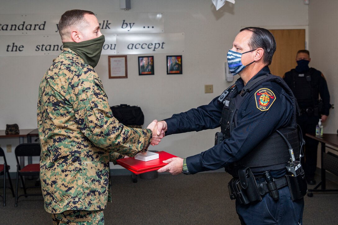 U.S. Marine Corps Lt. Col. Matthew Dowden, left, commanding officer of 2nd Tank Battalion, 2nd Marine Division, presents Michael Walusz, right, a police officer with the Marine Corps Base Camp Lejeune Provost Marshal’s Office (PMO), the Lifesaving Award at PMO on MCB Camp Lejeune, North Carolina, Dec. 16, 2020. Walusz received the award for his life-saving actions following an accident in which a Marine with 2nd Tank Battalion was severely injured. (U.S. Marine Corps photo by Lance Cpl. Christian Ayers)