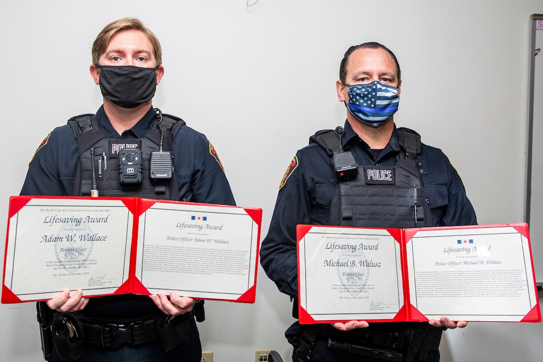 Adam Wallace, left, and Michael Walusz, right, police officers with the Marine Corps Base Camp Lejeune Provost Marshal’s Office, pose for a photo after being awarded the Lifesaving Award at the Provost Marshal’s Office on MCB Camp Lejeune, North Carolina, Dec. 16, 2020. The police officers received the award for their life-saving actions following an accident in which a Marine with 2nd Tank Battalion was severely injured. (U.S. Marine Corps photo by Lance Cpl. Christian Ayers)