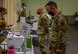 Airmen stand in front of check-in tables.