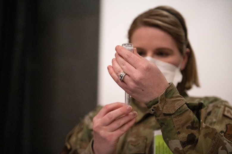 airman draws vaccine from vial