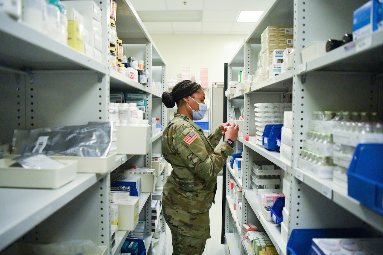 A soldier reviews medications on shelves.