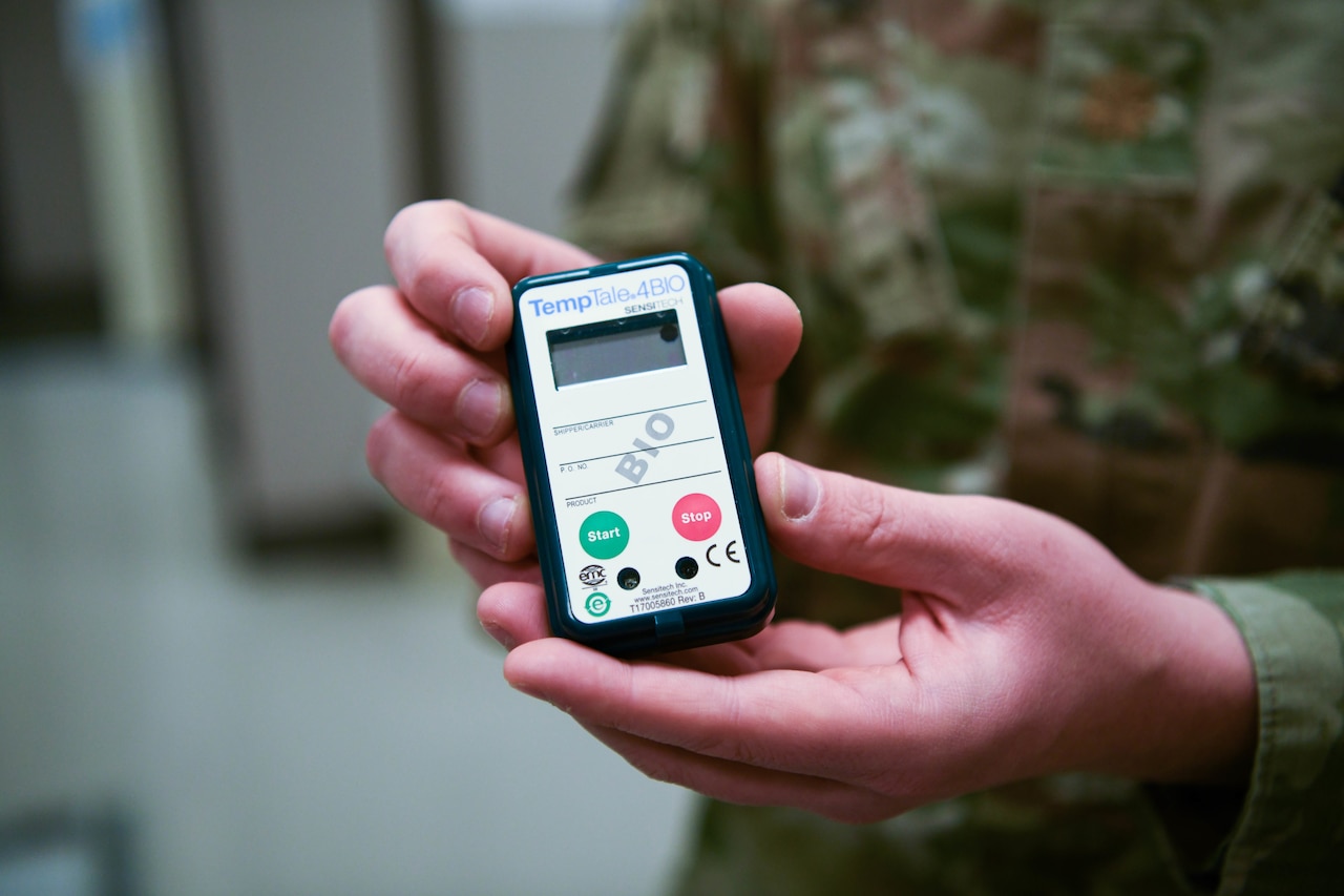 A soldier holds a temperature check device.