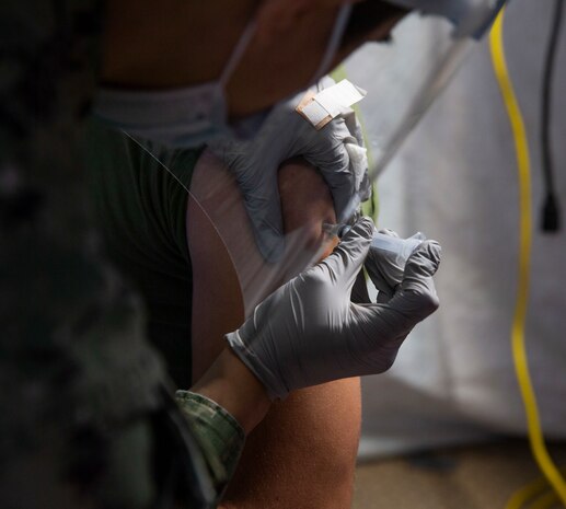 U.S. Navy Seaman Jose Acosta, a hospital corpsman with U.S. Naval Hospital Okinawa, administers the Moderna COVID-19 vaccine to U.S. Marine Corps and Navy medical personnel and first responders at the U.S. Naval Hospital Okinawa on Camp Foster, Okinawa, Japan, Dec. 29, 2020. The Department of Defense’s (DOD) COVID-19 vaccination plan is phase driven and designed to protect members within the DOD from COVID-19 as quickly and safely as possible in order to bolster mission readiness and enhance capabilities of DOD members worldwide. (U.S. Marine Corps photo by Lance Cpl. Alex Fairchild)
