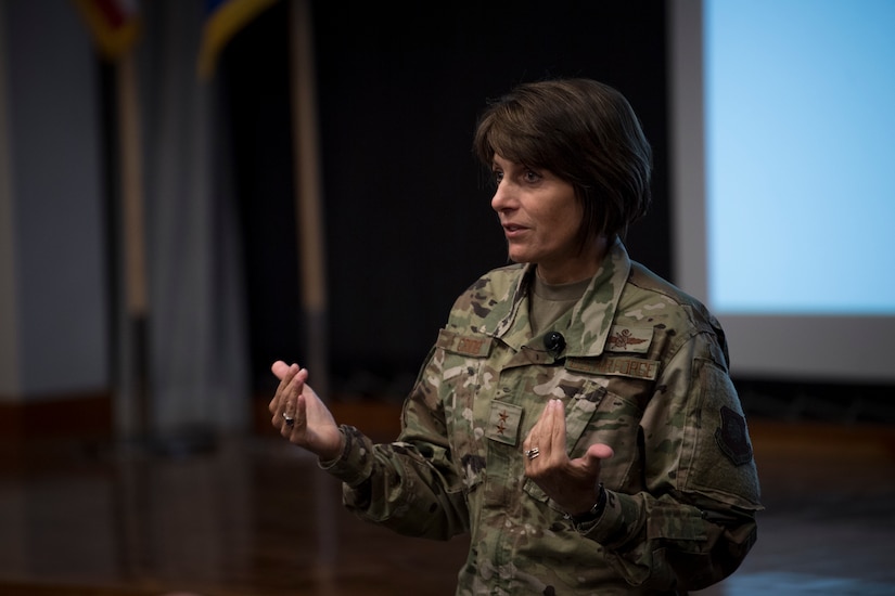 A woman in a combat uniform speaks in an auditorium.