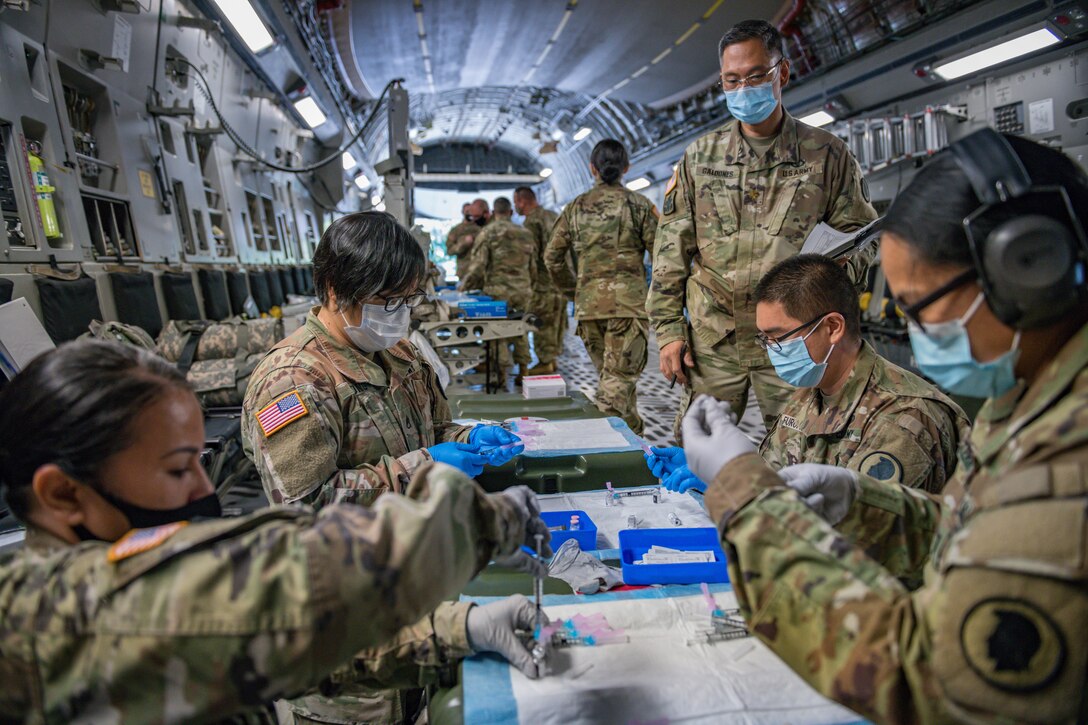 A group of service members fill syringes with vaccine.