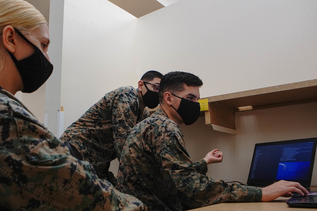 U.S. Marine Corps Lance Cpl. Ian Bergman, middle, a defensive cyberspace operator, Lance Cpl. Enrique Medina, right, a defensive cyberspace operator, and Cpl. Bethany Leer, left, an intelligence analyst with 9th Communication Battalion, I Marine Expeditionary Force Information Group, hack into a system while engaged in the Marine Corps 2020 Cyber Games at Marine Corps Base Camp Pendleton, California, Nov. 19, 2020. 9th Comm participated in the cyber games to enhance their skills and to develop tactics and techniques while competing against other teams across the United States. (U.S. Marine Corps photo by Lance Cpl. Patrick Katz)