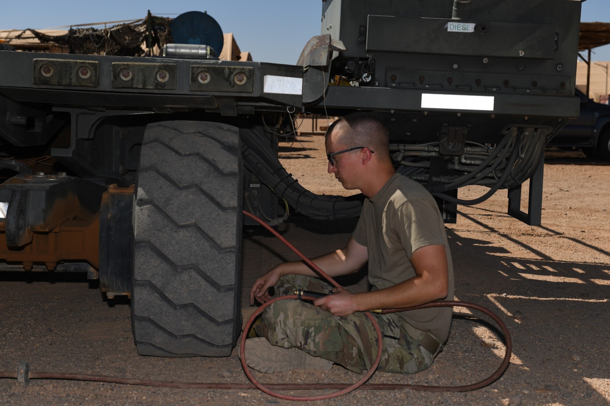 U.S. Air Force Senior Airman Ryan Davis, 724th Expeditionary Air Base Squadron air terminal operations center journeyman, puts air in a Halvorsen 25K-Loader tire, at Nigerien Air Base 201, Agadez, Niger, Jan 4, 2021. These machines are used to upload and download pallets, pallet trains, and rolling stock on cargo aircraft. (U.S. Air Force photo by Senior Airman Gabrielle Winn)