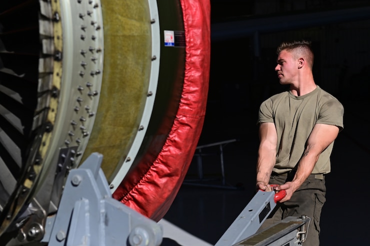 Photo of an Airman pulling a jet engine into a hangar