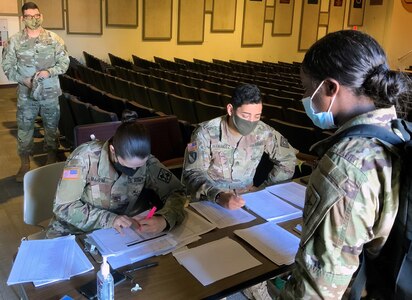 Pfc. Shavarianna Burton is greeted at the first station for Holiday Block Leave reintegration screening as Lt. Col. Nadia M Pearson, MEDCoE command surgeon and Command Sgt. Major Gilberto Colon, 32nd Medical Brigade Command Sergeant Major, look on.