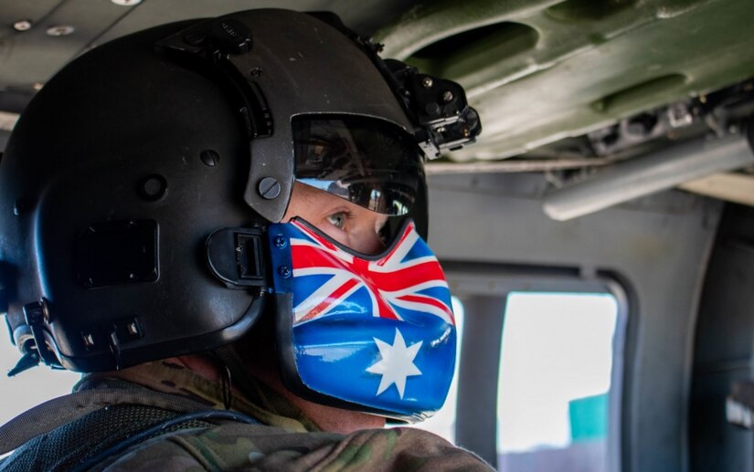 A National Guardsman shown in profile wears a helmet with an Australian flag over the mouthpiece.