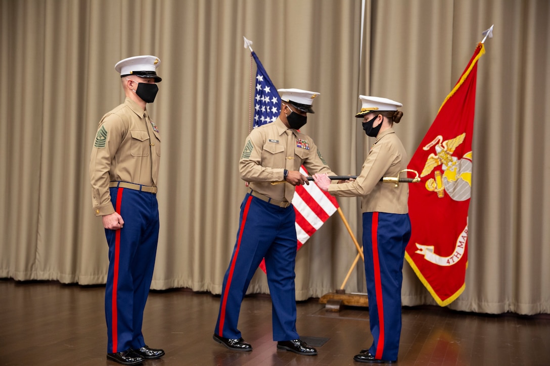 U.S. Marine Sgt. Maj. Chester Wilson III, center, outgoing district sergeant major, passes a sword to Col. Heather J. Cotoia, right, commanding officer 4th Marine Corps District, during a relief and appointment ceremony at the Defense Logistics Agency, New Cumberland, Pennsylvania, Dec. 22, 2020. Sgt. Maj. Kenneth L. Kuss took over the 4th Marine Corps District senior enlisted advisor position from Wilson. (U.S. Marine Corps photo by Gunnery Sgt. Valerie Nash)