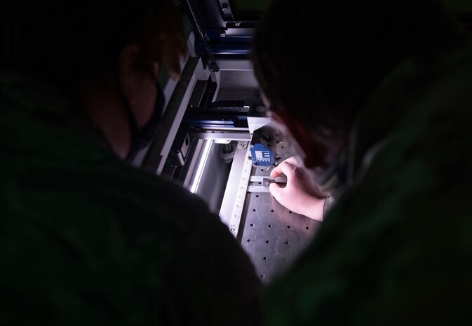 Airman 1st Class Hannah Kinter, left, and Senior Airman Adam Sherman, 9th Aircraft Maintenance Squadron (AMXS) support technicians prepare to laser engrave a tool on Beale Air Force Base.