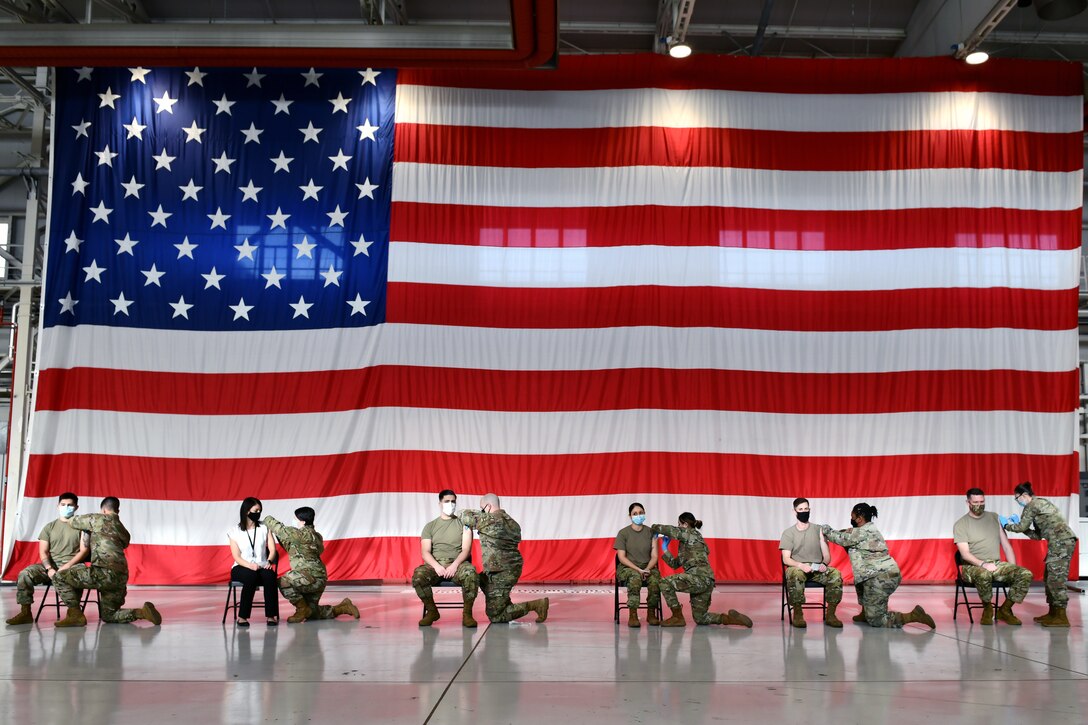 Six Air Force airmen simultaneously receive COVID-19 vaccines.