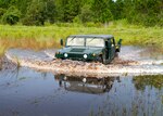 A Humvee drives through water up to it's headlights.