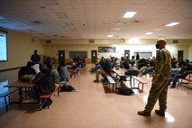 A man stands near a seated group watching a slideshow