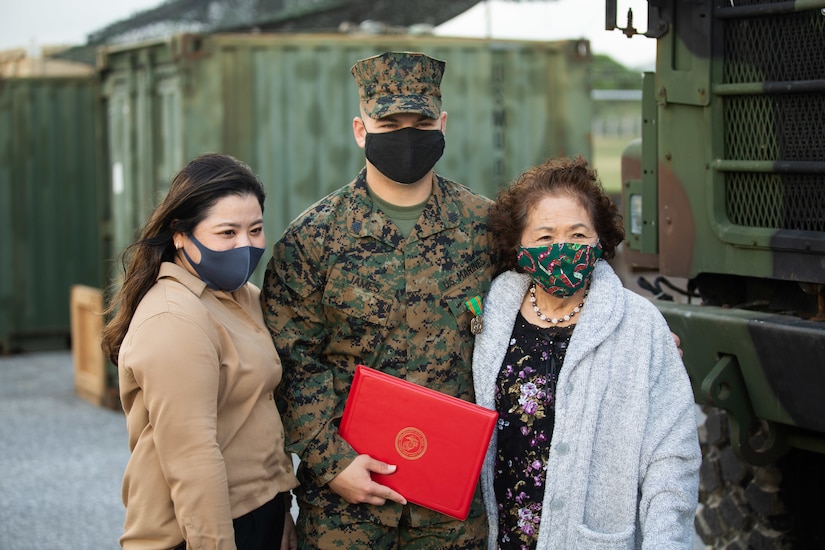 A Marine stands with two women.