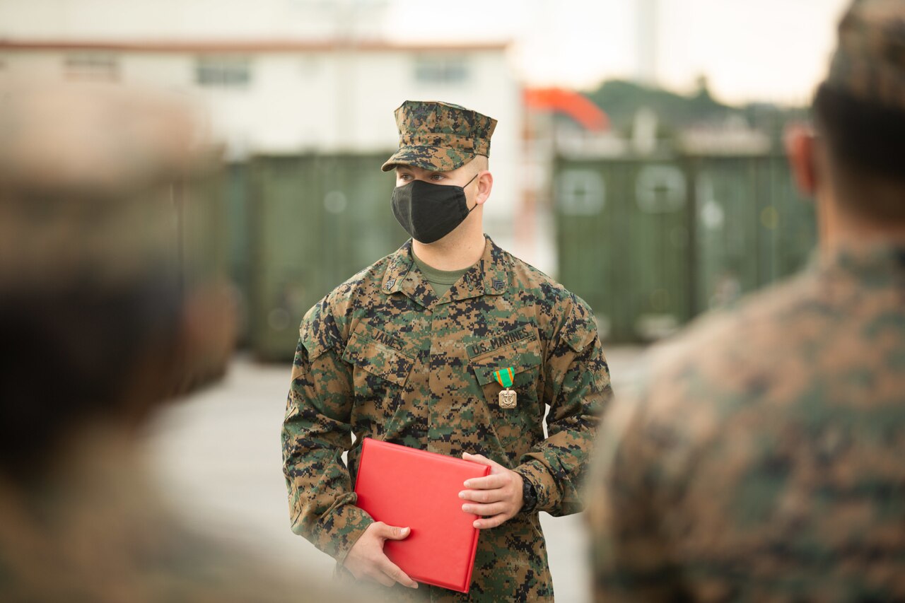 A Marine wearing a medal holds a red folder.