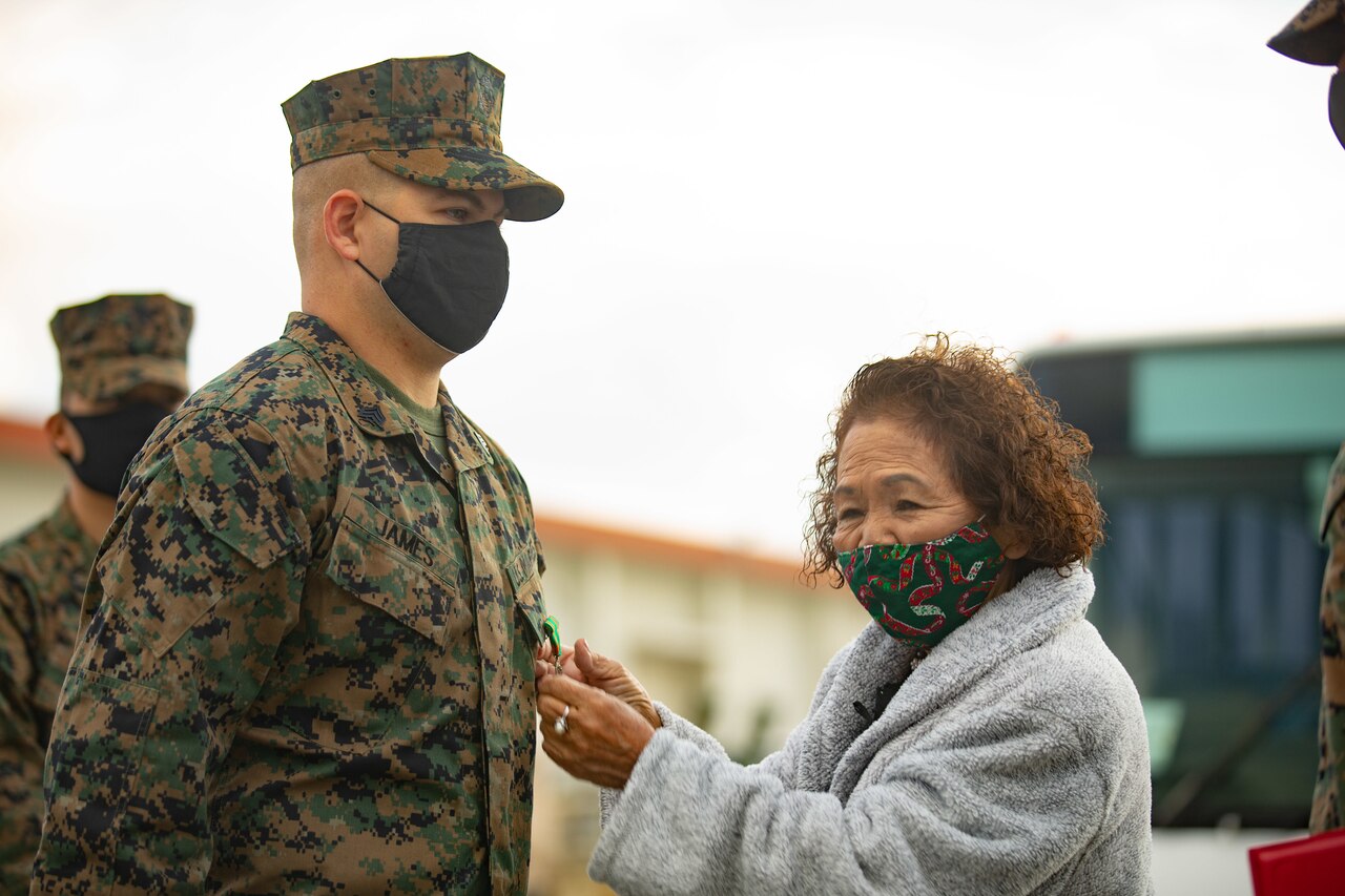 A woman pins a medal on a Marine.