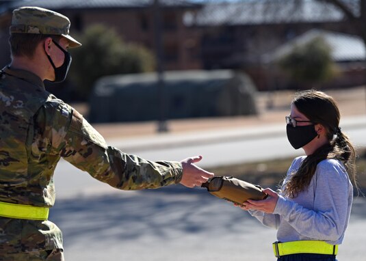 U.S. Air Force Airman Silas Poock, 316th Training Squadron student, hands a goody bag to an Airman during the distribution of donated goods from the USO at the Cressman Dining Facility on Goodfellow Air Force Base, Texas, Jan. 7, 2021. The bags were filled with a variety of candy, and snacks members could enjoy in their dorms. (U.S. Air Force photo by Airman 1st Class Ethan Sherwood)