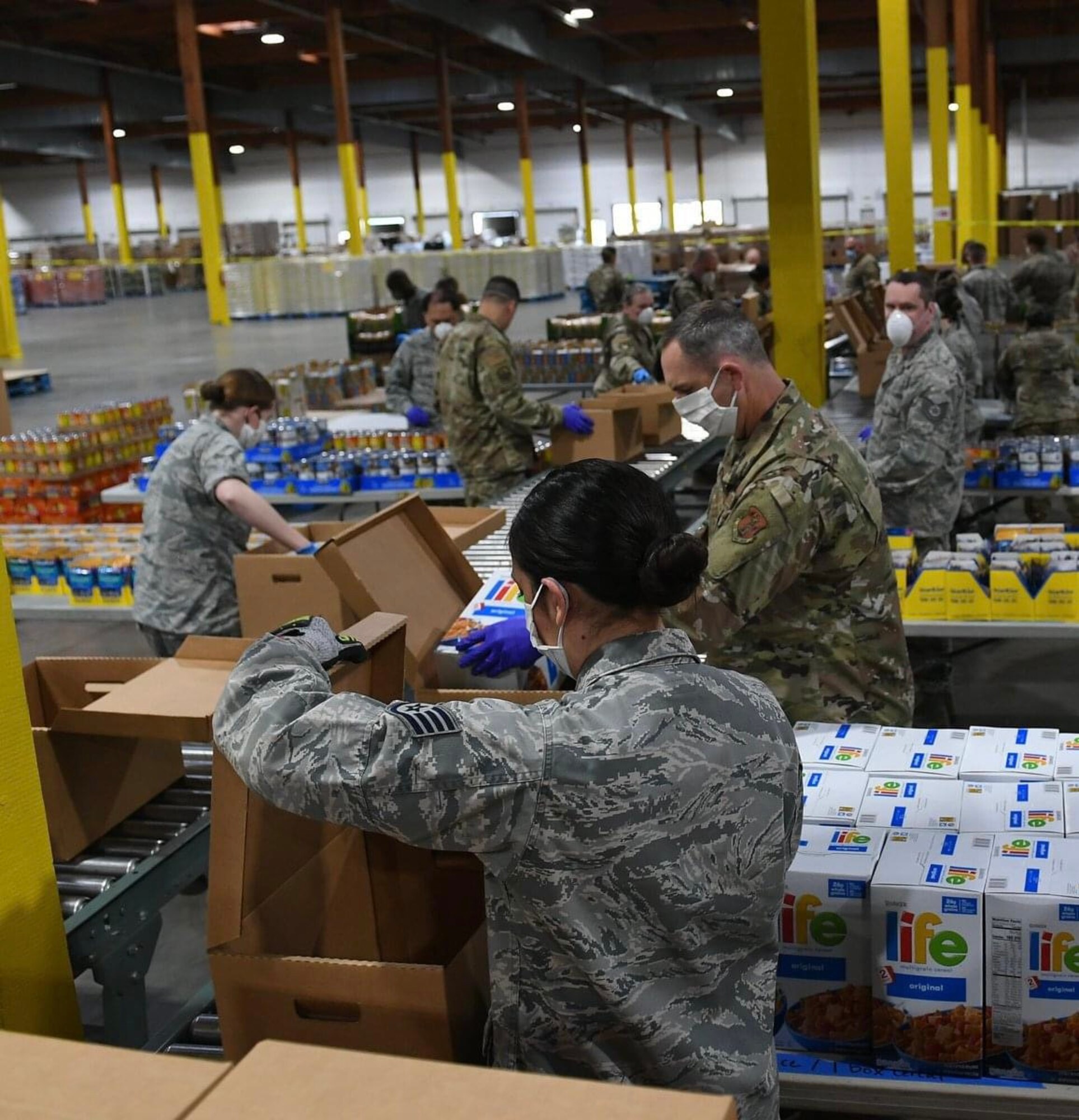 Air National Guardsmen prepare food boxes at the Food Lifeline Covid Response