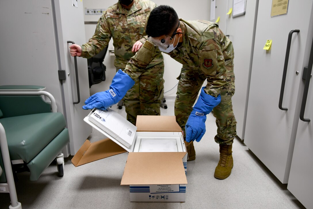 Senior Airman Siejeay Dimla, 31st Medical Support Squadron medical logistics technician, opens a case containing COVID-19 vaccines at Aviano Air Base, Italy, Jan. 7, 2021.