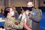 An airman gives a COVID-19 vaccine to a senior Air Force officer
