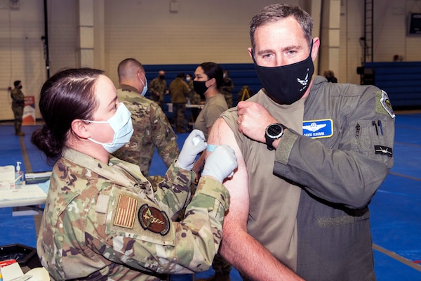 An airman gives a COVID-19 vaccine to a senior Air Force officer