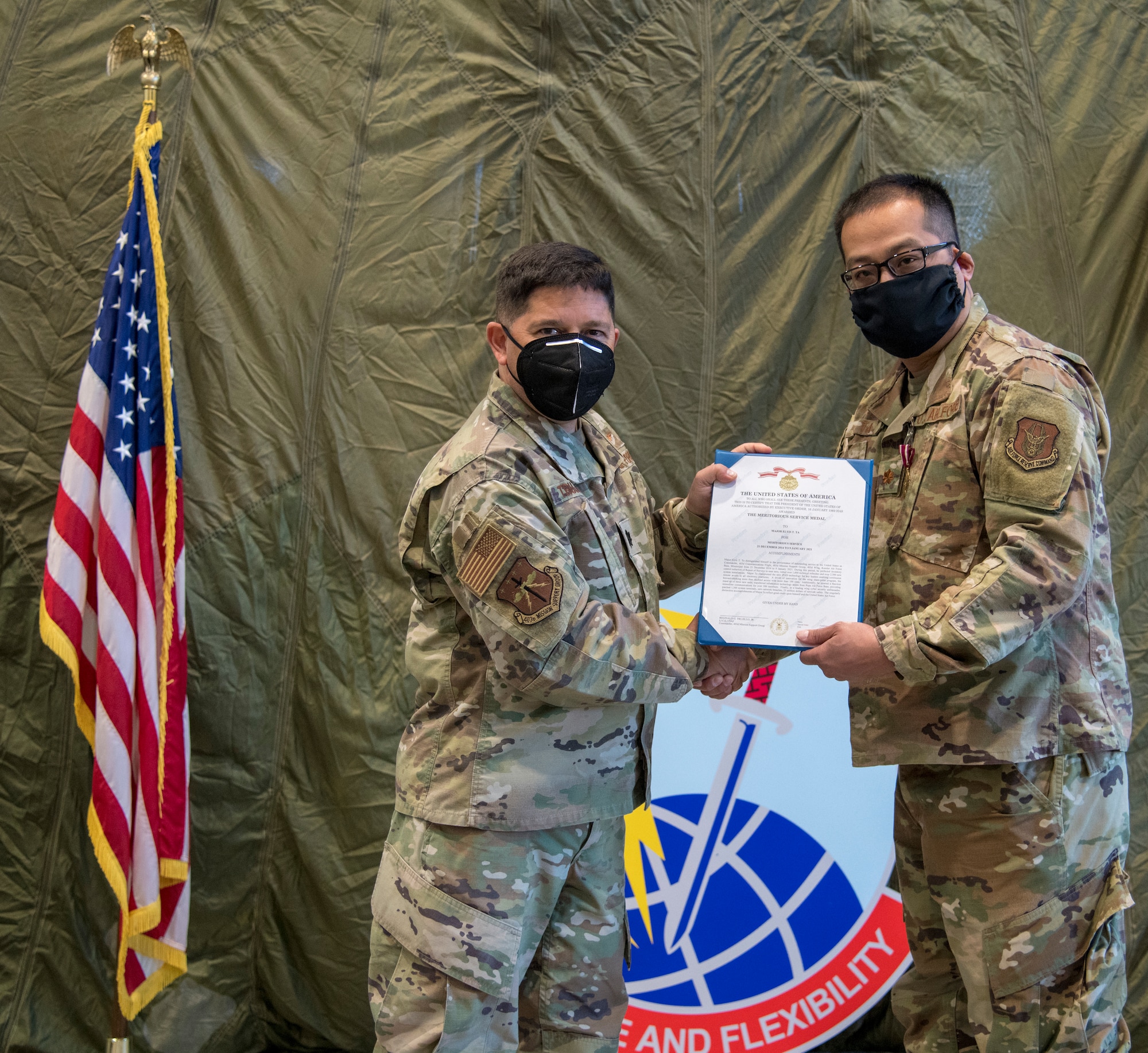 Lt. Col. Reginald Trujillo, 403rd Mission Support Group commander, presents Maj. Elvis Ta, outgoing 403rd Communications Flight commander, with an Air Force Meritorious Servace Medal during a change of command ceremony at the 41st Aerial Port Squadron January 9, 2021. Ta served as the commander for the flight for 5 years. (U.S. Air Force photo by Senior Airman Kristen Pittman)