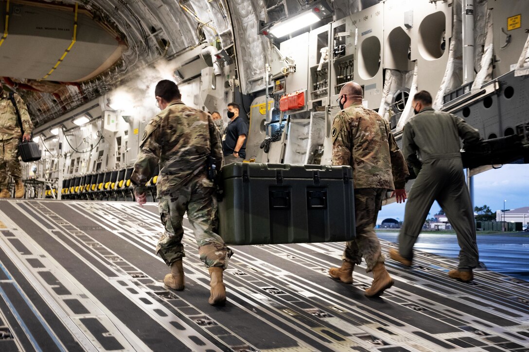 Soldiers carry COVID-19 vaccines onto a C-19 Globemaster III.