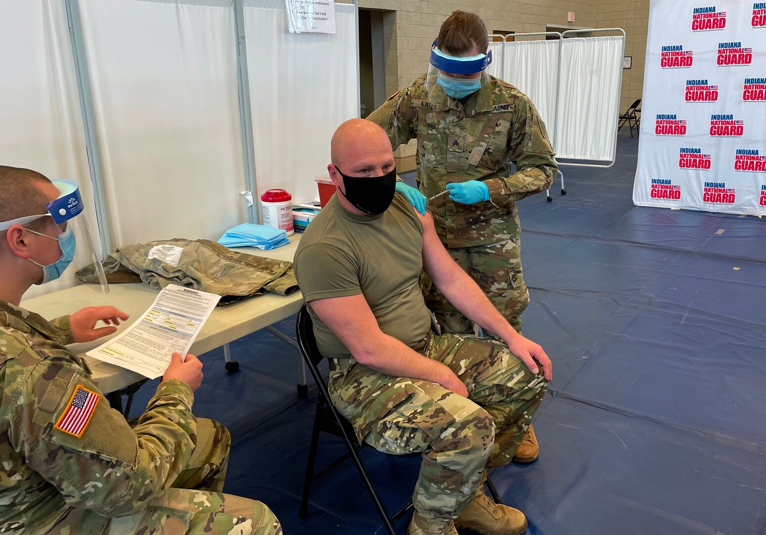 Indiana National Guard Sgt. Abigail Gates, a medic with 38th Infantry Division, administers a COVID-19 vaccination shot Dec. 16, 2020, in Franklin, Indiana, to Sgt. 1st Class Ben Cripe, an artilleryman. Hoosier Guardsmen have been critical to fighting the coronavirus pandemic, helping at food banks, distributing protective equipment, assisting long-term care facilities. They will now help distribute the coronavirus vaccine.</p>
