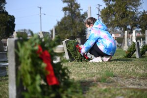 Cadence Smeltzer places a wreath over a veteran’s grave.