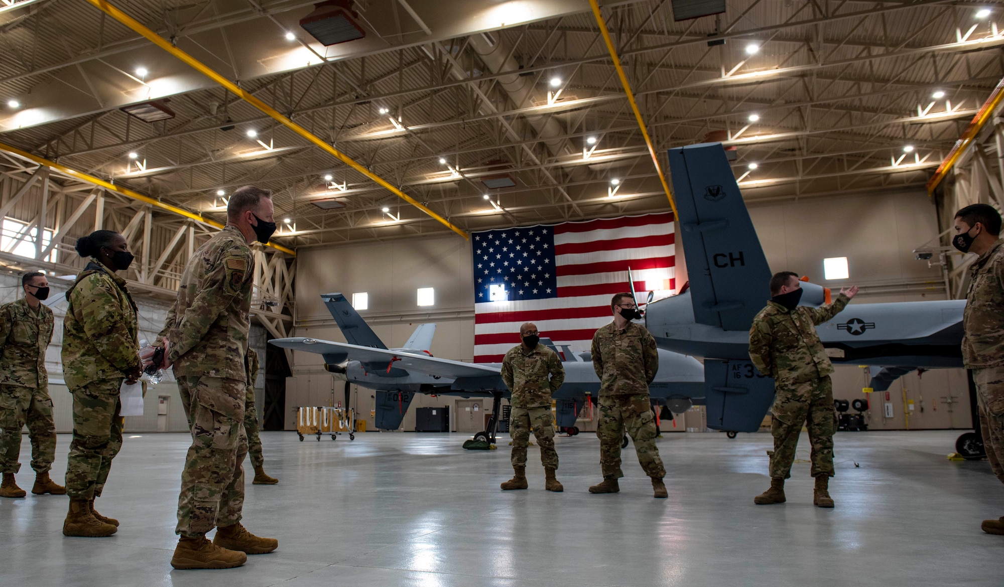 A group of Airmen stand in a hangar with an MQ-9 Reaper.