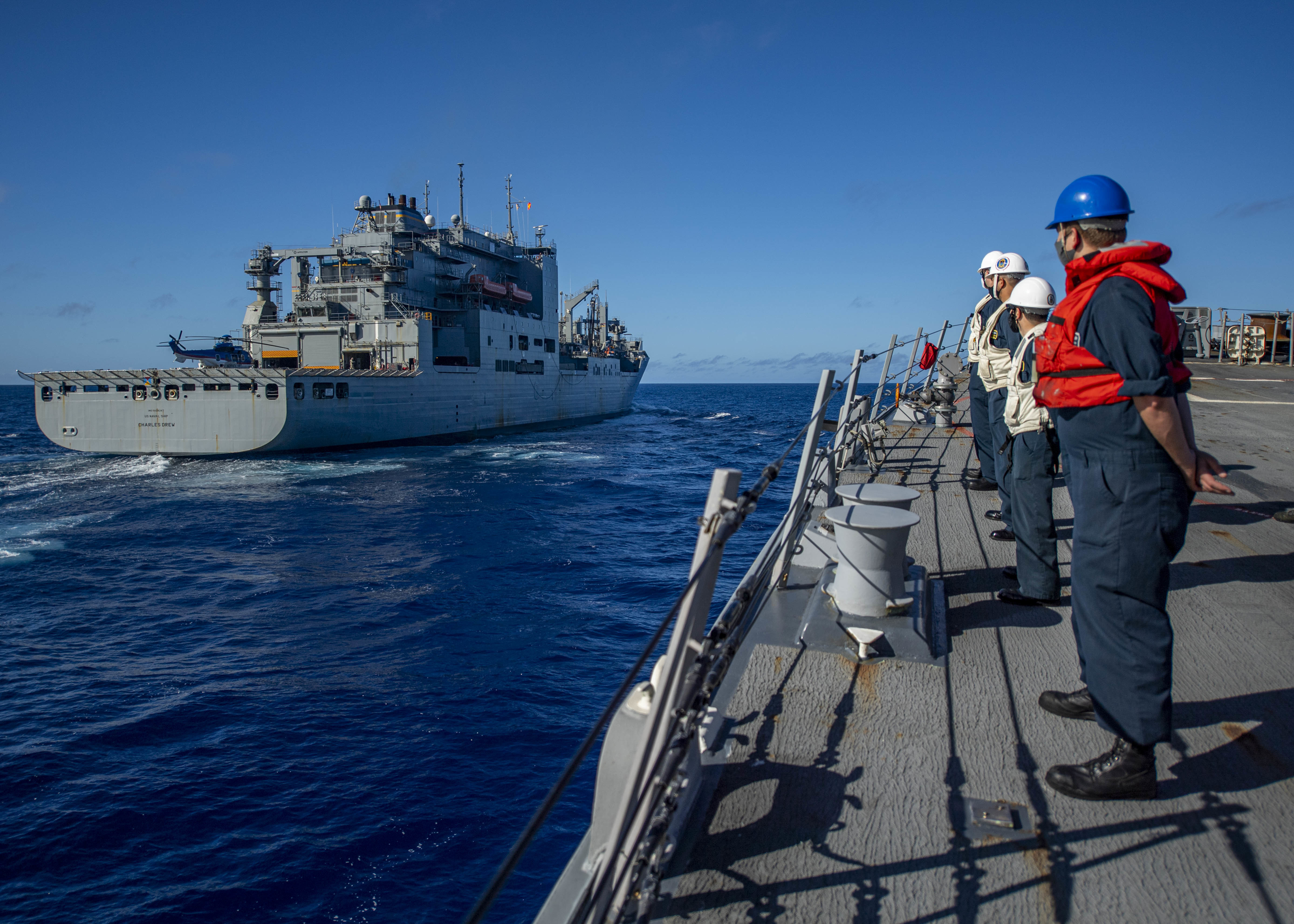 Sailors aboard the Arleigh Burke-class guided-missile destroyer USS John Finn (DDG 113) watch as the ship pulls alongside the Military Sealift Command dry cargo and ammunition ship USNS Charles Drew (T-AKE 10) for a replenishment-at-sea Jan. 8, 2021.