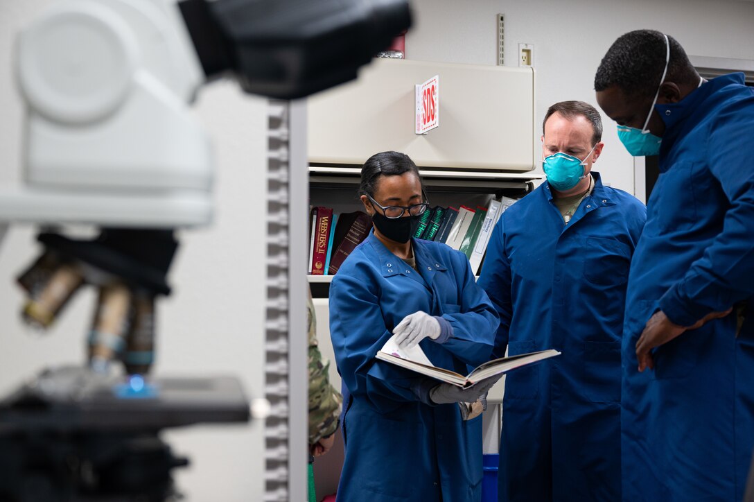 Airman 1st Class Olleah Brown, 47th Healthcare Operations Squadron laboratory technician, references a medical book with Col. Craig Prather, 47th Flying Training Wing commander, and Chief Master Sgt. Brian Lewis, 47th Operations Group superintendent, at Laughlin Air Force Base, Texas, Jan. 8, 2021. Col. Prather and CMSgt. Lewis learned about standard procedures including blood sampling and urinalysis. (U.S. Air Force photo by Senior Airman Marco A. Gomez)