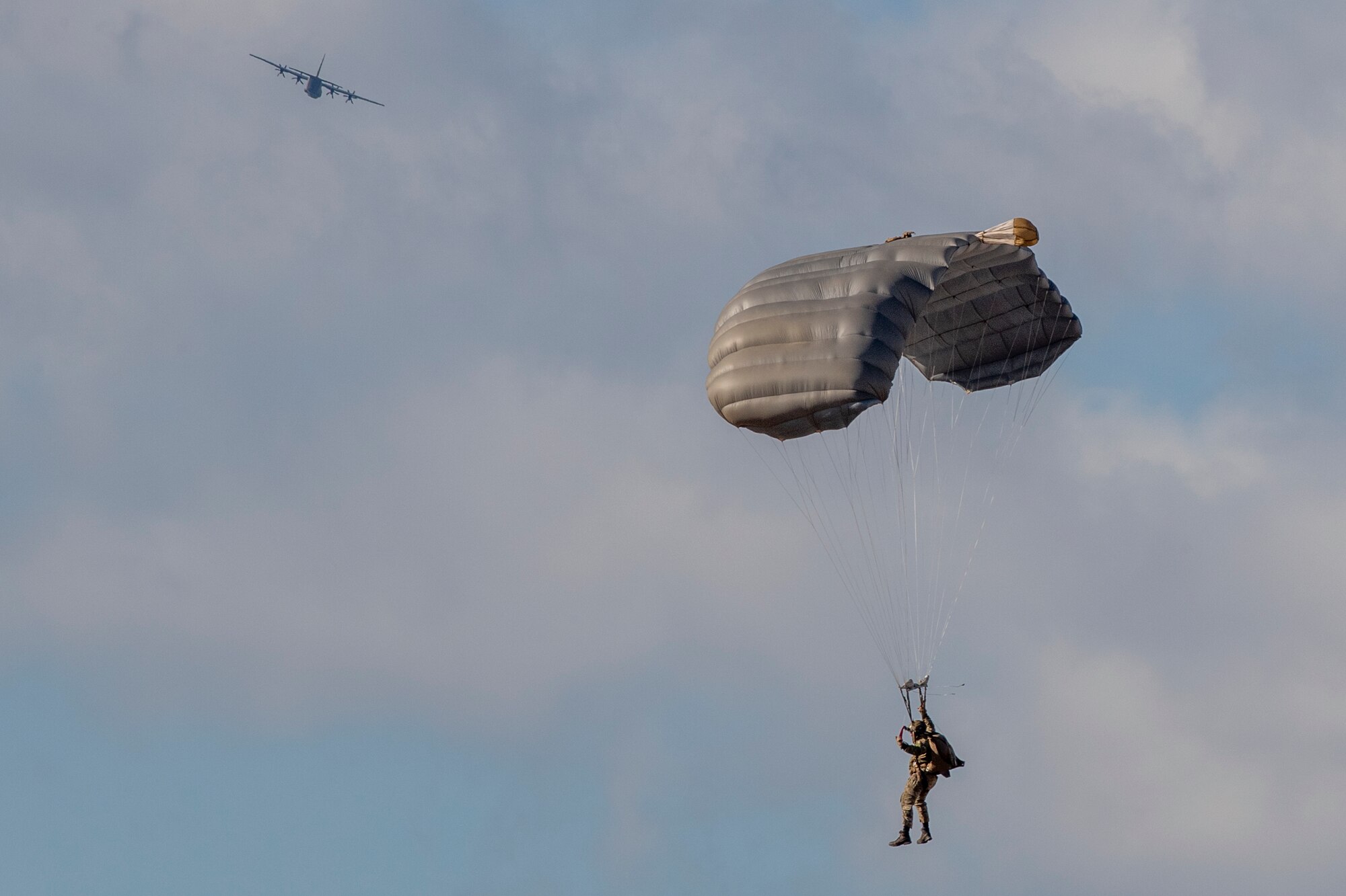 Soldier parachuting below C-130J Super Hercules
