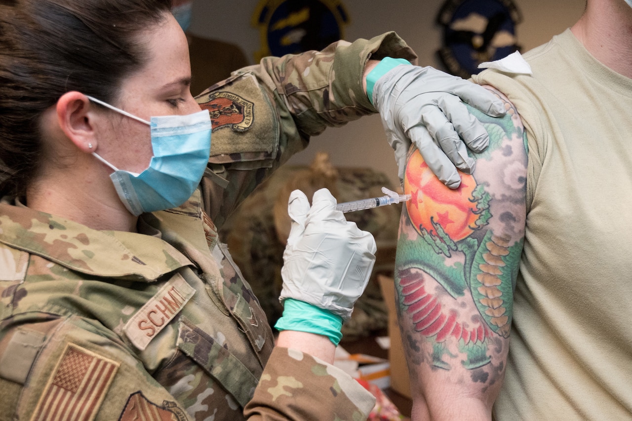 An airman vaccinates a fellow airman.