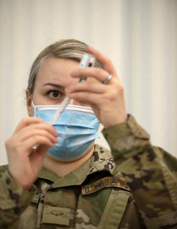 An airman loads a syringe with the Moderna COVID-19 vaccine.