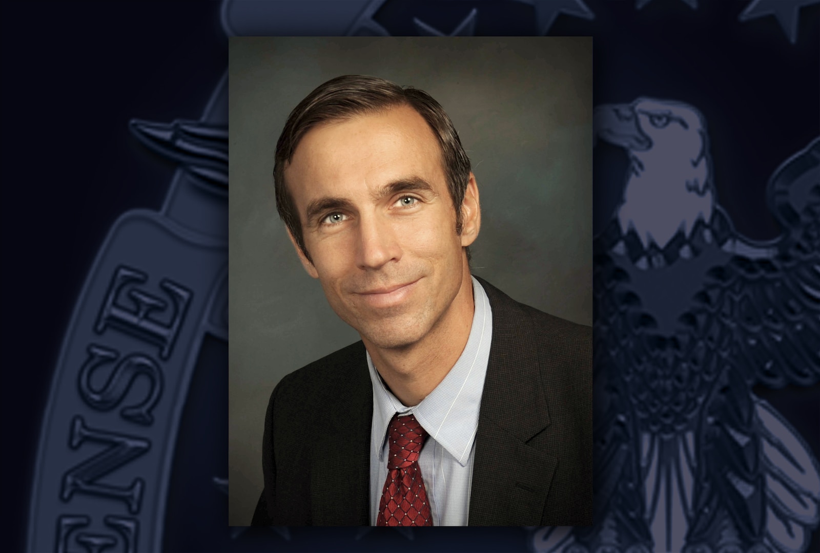 Head and shoulders image of a white man wearing red tie, white shirt and black suit jacket.