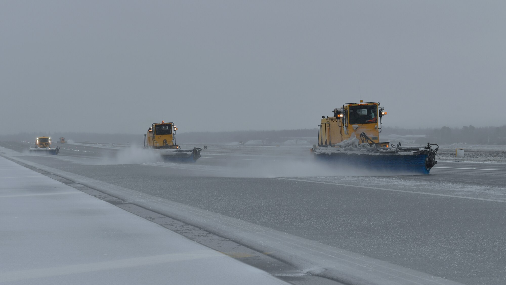 A snowplow removing snow from a runway
