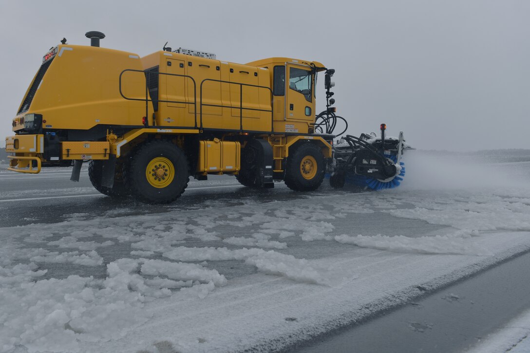 A snowplow removing snow from a runway