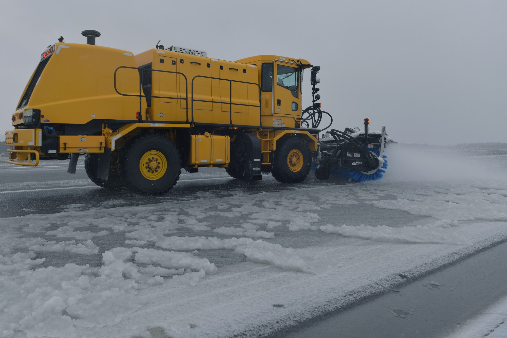 A snowplow removing snow from a runway