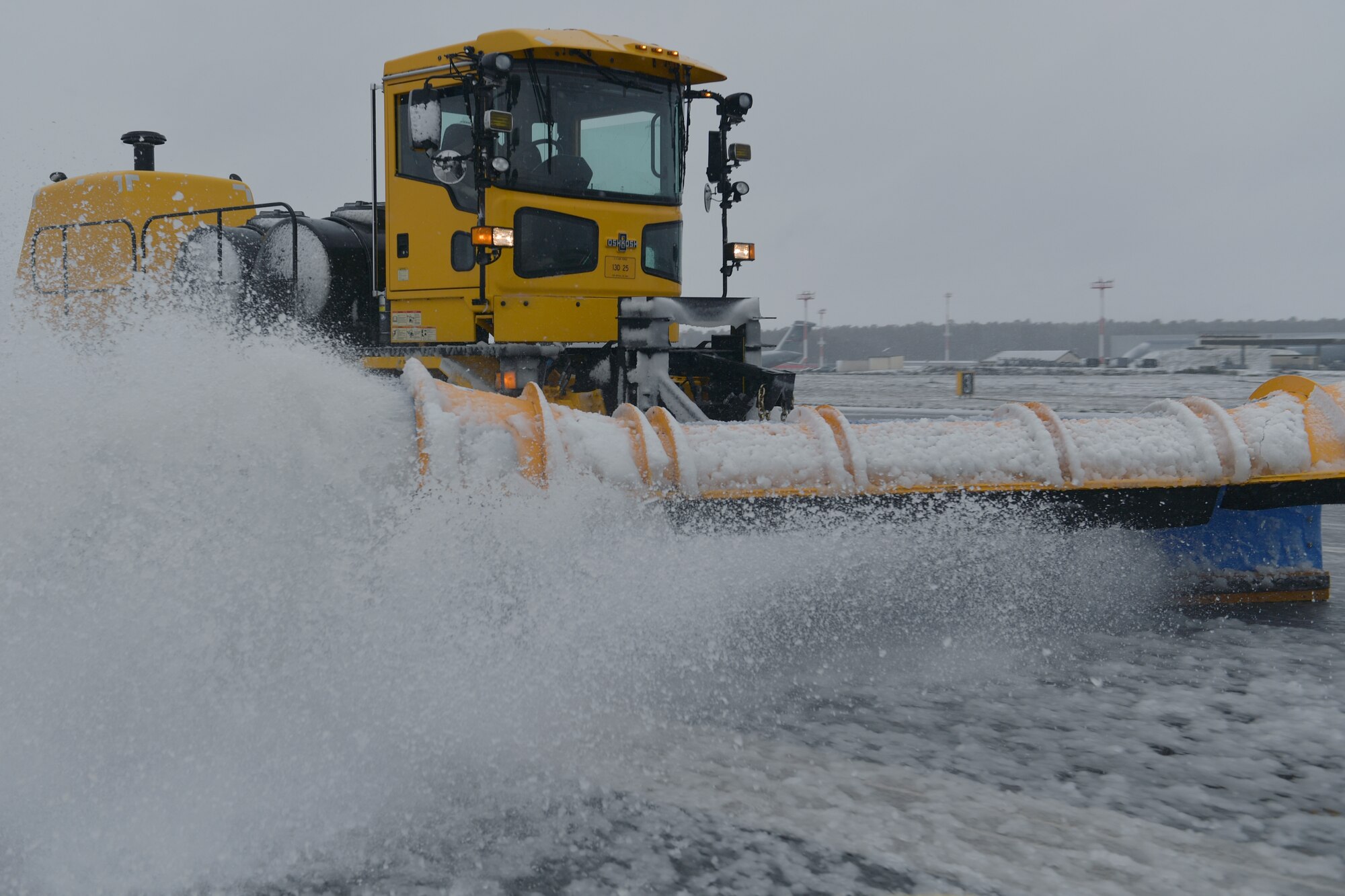 A snowplow removing snow from a runway