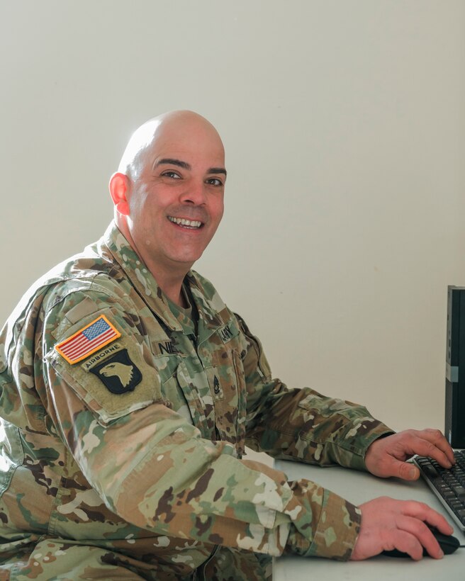 A seated soldier smiles for the camera.