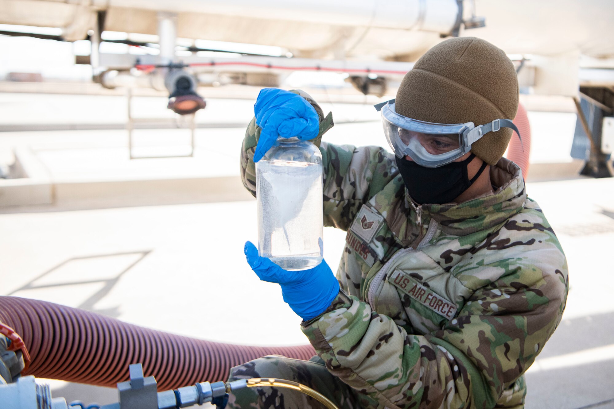 An Airman swirls a jar of fuel while doing a visual test of its quality