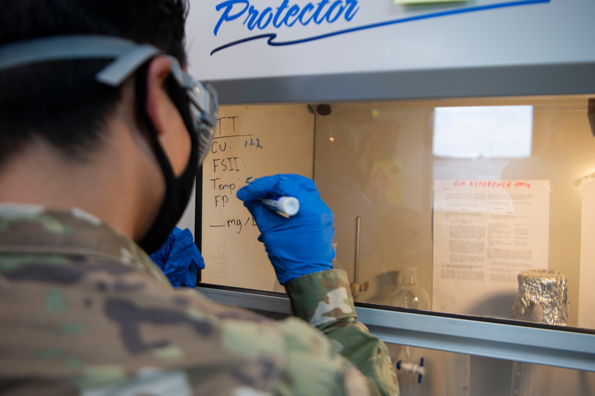 An Airman writes down notes during his lab testing of fuel