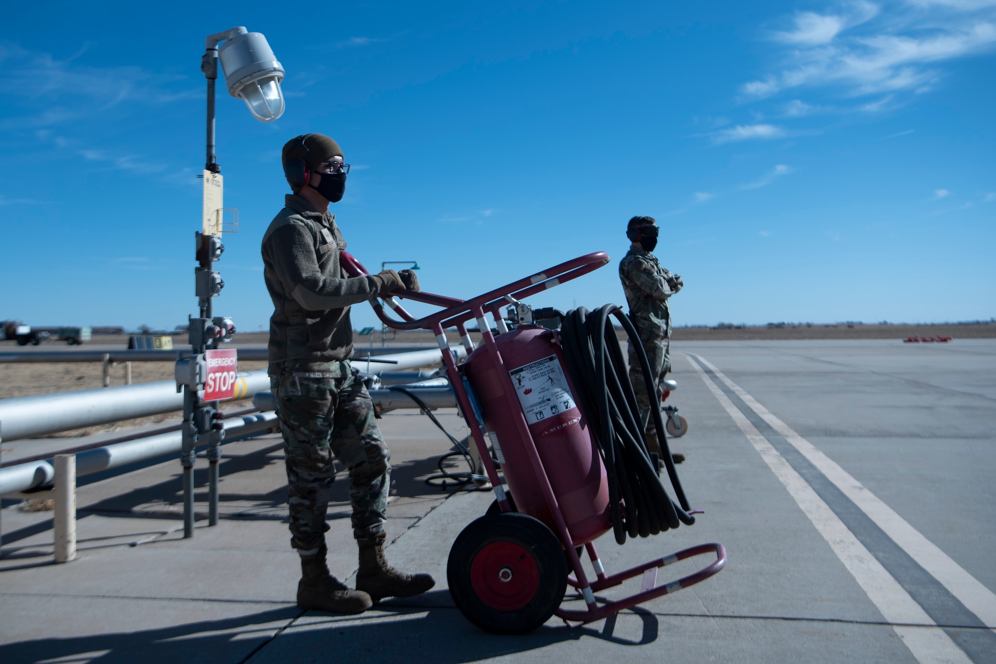Two Airman standby as the wait for a plane to land so they can refuel it